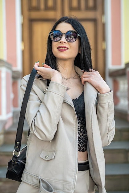 Fashionable woman wear white leather jacket against old vintage house of city