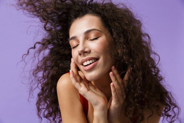 fashionable woman wearing red dress laughing, standing isolated over violet wall