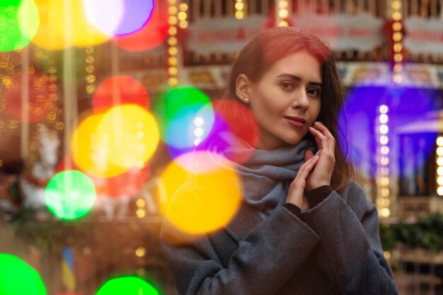 Fashionable woman wears grey coat walking at the street with\
bokeh light. empty space