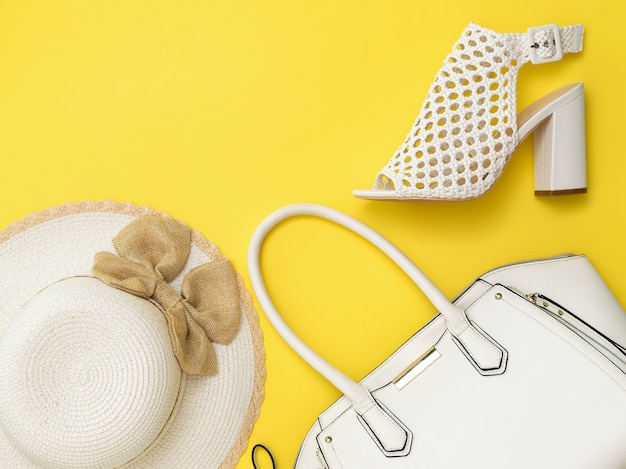 Foto cappello, borsa e scarpe delle donne alla moda su fondo giallo. vestiti e accessori alla moda per le donne. lay piatto.