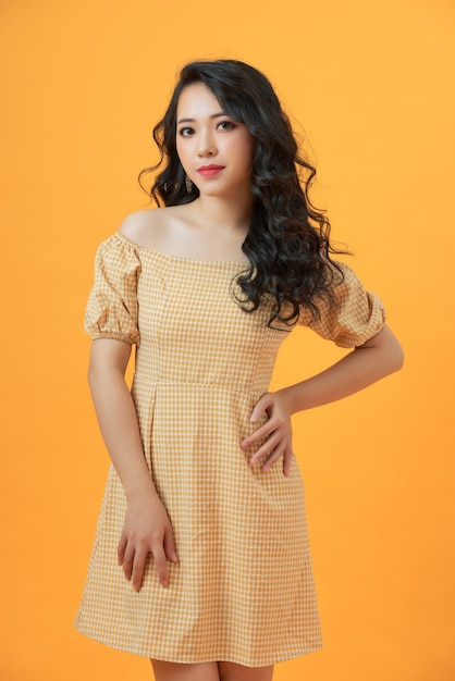Fashionable young beautiful model posing on yellow wearing dress