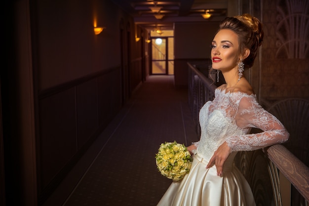 Fashionable young blonde bride in wedding dress with roses in her hands