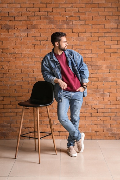 Fashionable young man near brick wall