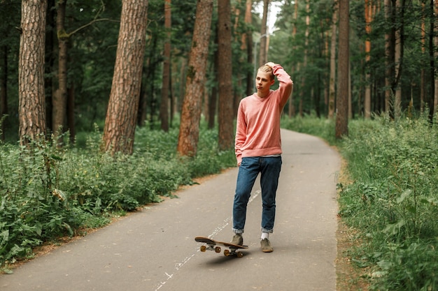 Fashionable young man with a skateboard ride in the park