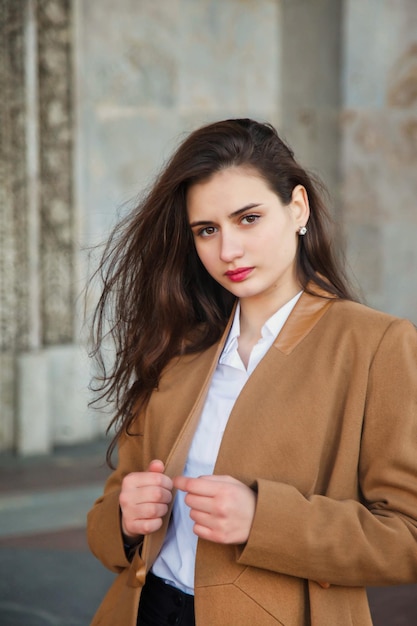 Fashionable young pretty stylish woman in orange fall coat posing on street