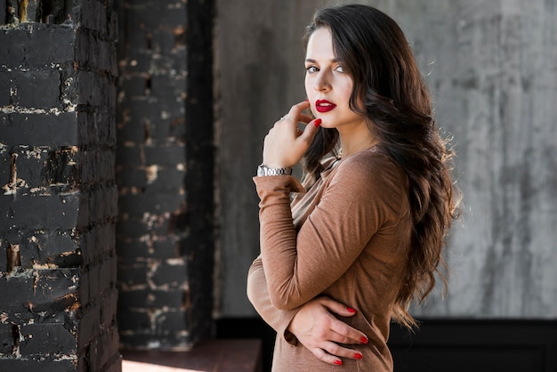 Photo fashionable young woman standing against wall