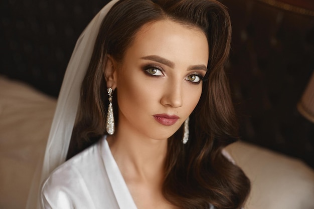 A fashionable young woman with perfect long wavy hair and perfect trendy makeup in an elegant gown. Gorgeous model girl with red lips and deep seductive eyes.