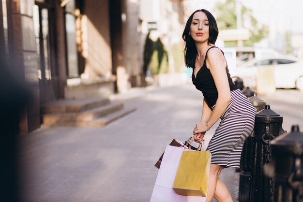 Fashionably dressed woman with colored shopping bags on the streets, shopping concept