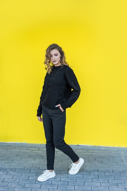 Fashional portrait of pretty lady near yellow wall