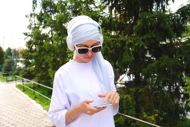 A fasion modren muslim woman in hidjab watching video and listening by mobile phone outdoor