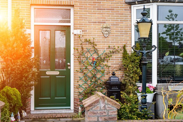 Foto fassade van een typisch nederlands deurhuis met bakstenen muren, trappen, voordeur, ramen, deuren op de straat, nederland