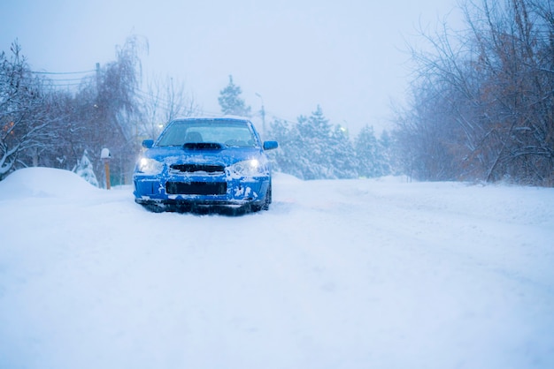 A fast blue sport car on winter snowy day, cold season, street road