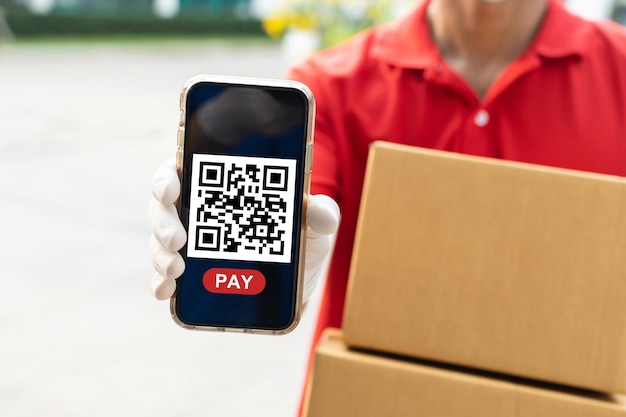 Fast delivery service man holding parcel post box waiting for customer scan QR code on mobile phone for online payment at door home, fast delivery service, express delivery, online shopping concept