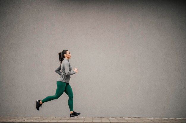 A fast female runner is running on the city street downtown