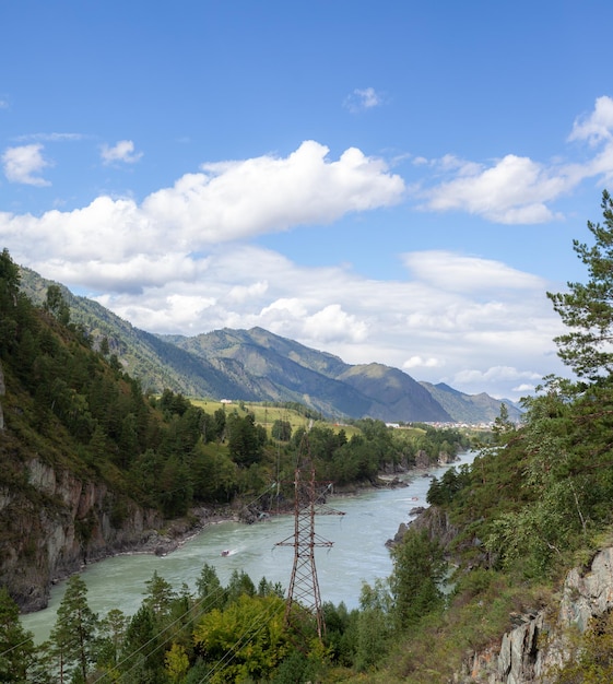 A fast-flowing wide and full-flowing mountain river. Large rocks stick out of the water.