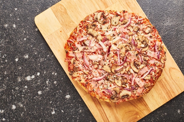 Fast food, Baked frozen pizza with ham, mushrooms and cheese on thick dough. Ready to eat. Flatlay.