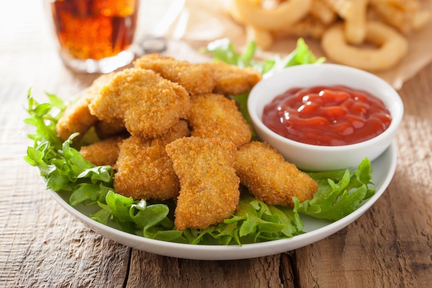 Fast food chicken nuggets with ketchup, french fries, cola