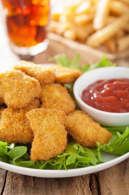 Fast food chicken nuggets with ketchup, french fries, cola