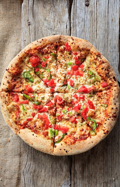 Fast food concept Pizza with crunchy dough and fresh vegetables on wooden surface