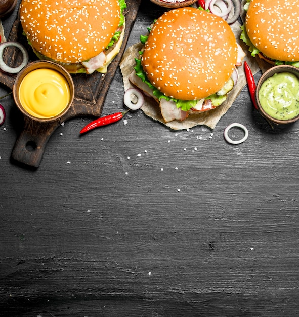 Fast food. Diverse hamburgers met sauzen. Op het zwarte bord.