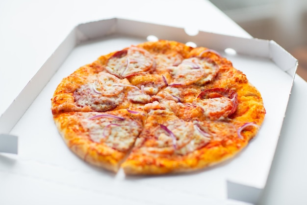 fast food, italian kitchen and eating concept - close up of pizza in paper box on table