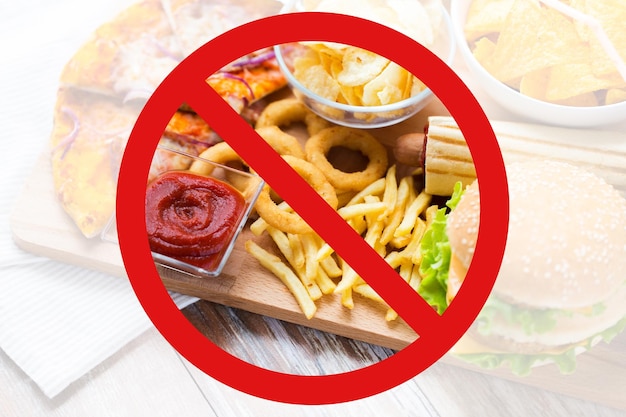 Photo fast food, low carb diet, fattening and unhealthy eating concept - close up of deep-fried squid rings, french fries and other snacks behind no symbol or circle-backslash prohibition sign