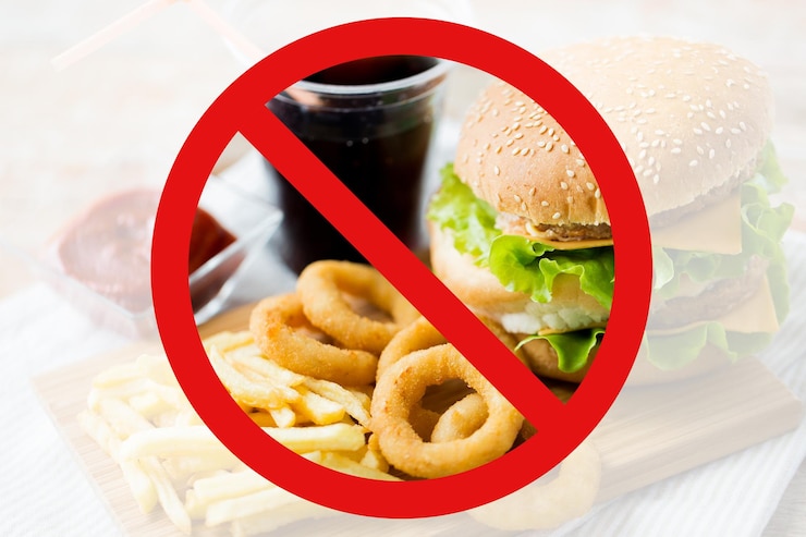 fast food, low carb diet, fattening and unhealthy eating concept - close up of hamburger or cheeseburger, deep-fried squid rings and french fries behind no symbol or circle-backslash prohibition sign