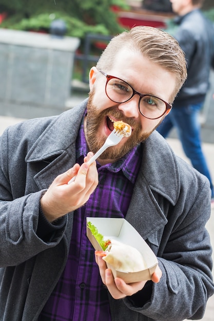 ファーストフードと食事のコンセプト-食べる若者は路上で食べ物をテイクアウトします。