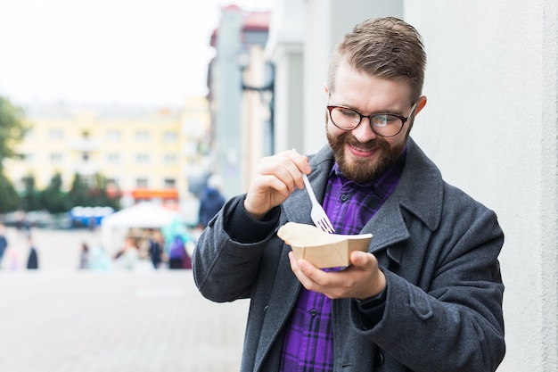 ファーストフードと食事のコンセプト-食べる若者は路上で食べ物をテイクアウトします。