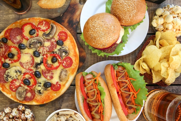 Fast food on old wooden background. Concept of junk eating. Top view. Flat lay.