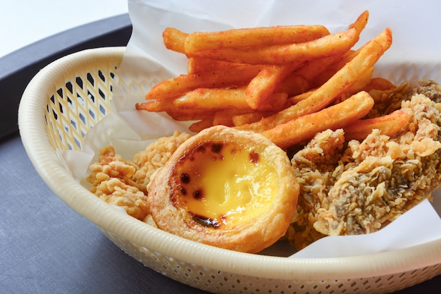 Fast food set in basket, crispy fried chicken, french fried and egg tart