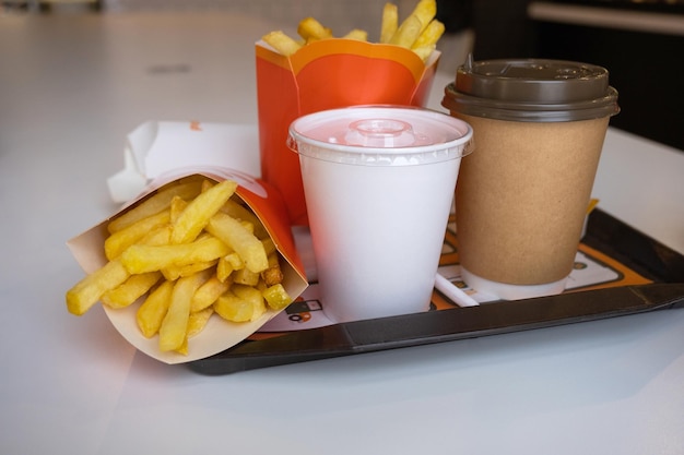 Fast food on a tray in a restaurant French fries a glass with a milkshake coffee