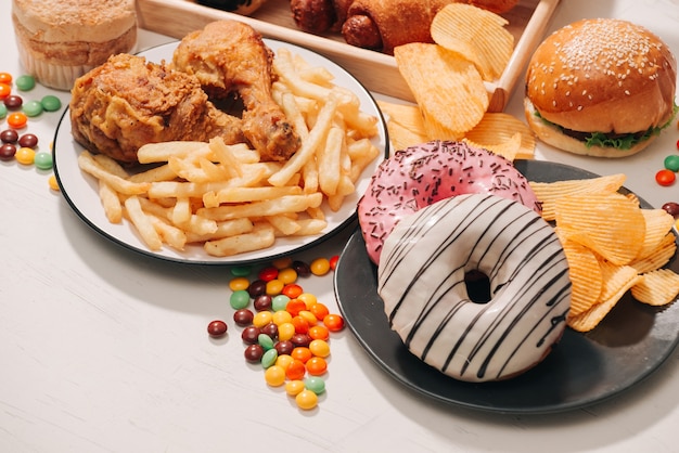 Fast food and unhealthy eating concept - close up of fast food snacks and cola drink on white table