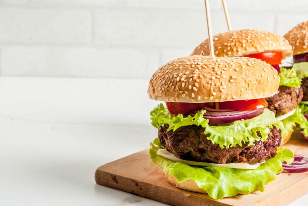 Фаст-фуд Нездоровая еда Вкусные свежие вкусные гамбургеры с говяжьей котлетой из свежих овощей и сыра на белом фоне