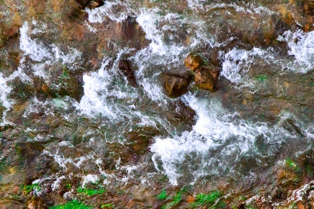 Fast mountain stream among rocks and plants a top view