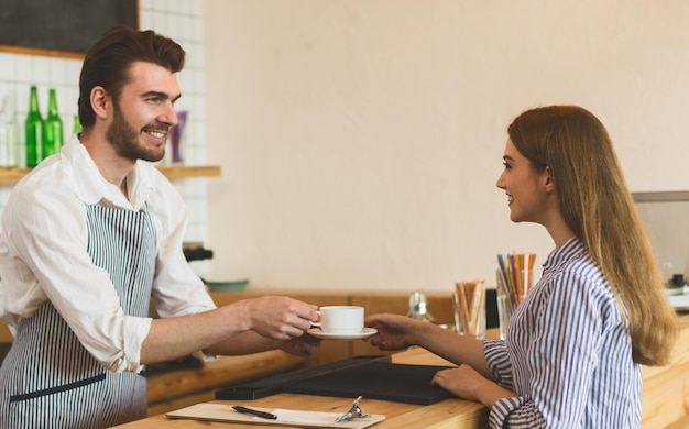 fast service. woman buying morning coffee in cafe and waiter widely smiling, copy space