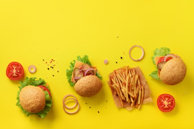 Fastfood banner. Sappige vleesburgers met rundvlees, tomaat, kaas, ui, komkommer en sla op gele achtergrond.