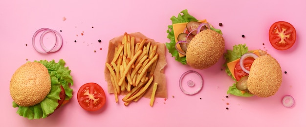 Fastfood banner. Sappige vleesburgers met rundvlees, tomaat, kaas, ui, komkommer en sla op roze achtergrond.