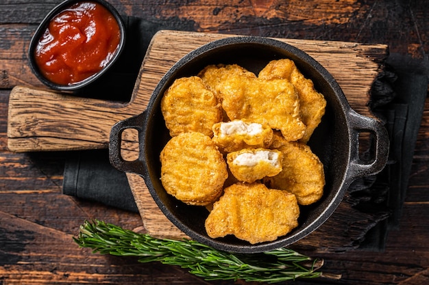 Fastfood pollo fritto pepite in padella sfondo in legno vista dall'alto