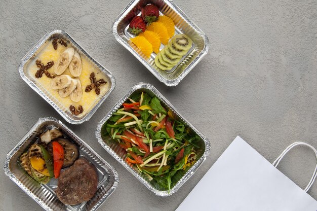 Fastfood in een foliedoos op een grijze achtergrond Levering vanuit het restaurant een set gezond voedsel