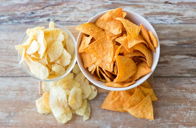 fastfood, junkfood, keuken en eetconcept - close-up van aardappelchips en maïsnacho's in kommen op tafel