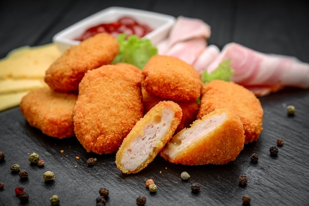 Fastfood kipnuggets met ketchup, tegen een donkere achtergrond