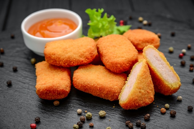 Fastfood kipnuggets met ketchup, tegen een donkere achtergrond