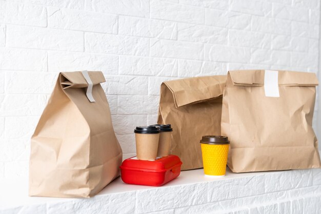 Fastfood verpakkingsset. Papieren koffiekopjes in houder, voedseldoos, bruine papieren zak op tafel.