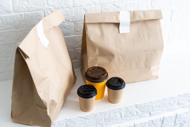 Fastfood verpakkingsset. Papieren koffiekopjes in houder, voedseldoos, bruine papieren zak op tafel.