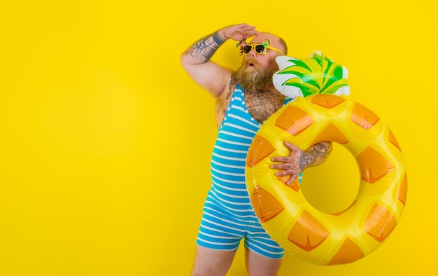 Fat amazed man with wig in head is ready to swim with a donut lifesaver