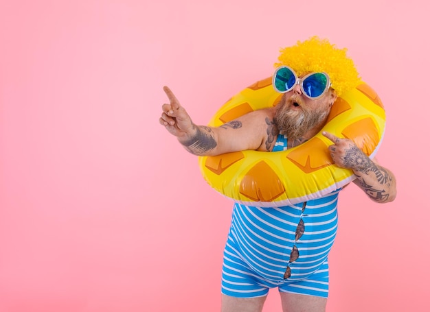 Fat amazed man with wig in head is ready to swim with a donut lifesaver