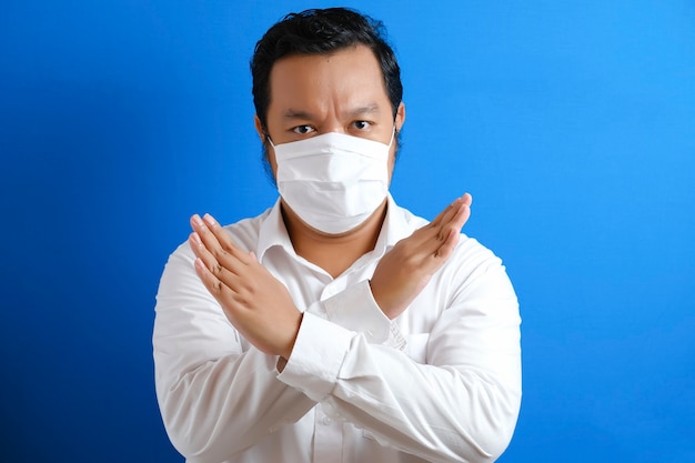 A fat Asian man wearing a mask to prevent transmission of the corona virus, by hand symbolizing stop gesture