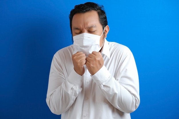 Fat Asian men wearing masks feel unwell. body gestures indicate fever. blue background