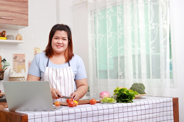 Donna asiatica grassa che cucina in cucina impara a preparare insalate e cibo sano dal concetto di assistenza sanitaria dei social media mangia cibo sano per perdere peso